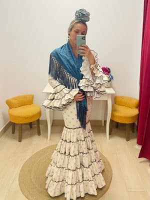 Mujer vestida con traje de flamenca canastero beis con lunar celeste y mantoncillo azul petróleo